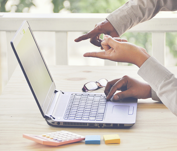 Two professionals pointing at information on laptop