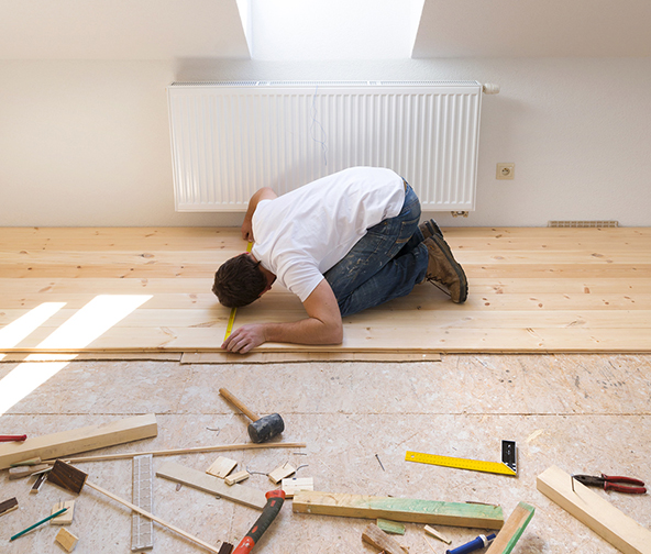 Professional taking measurements of a wood floor installation in progress