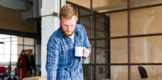 Individual reviewing blueprints and drinking coffee