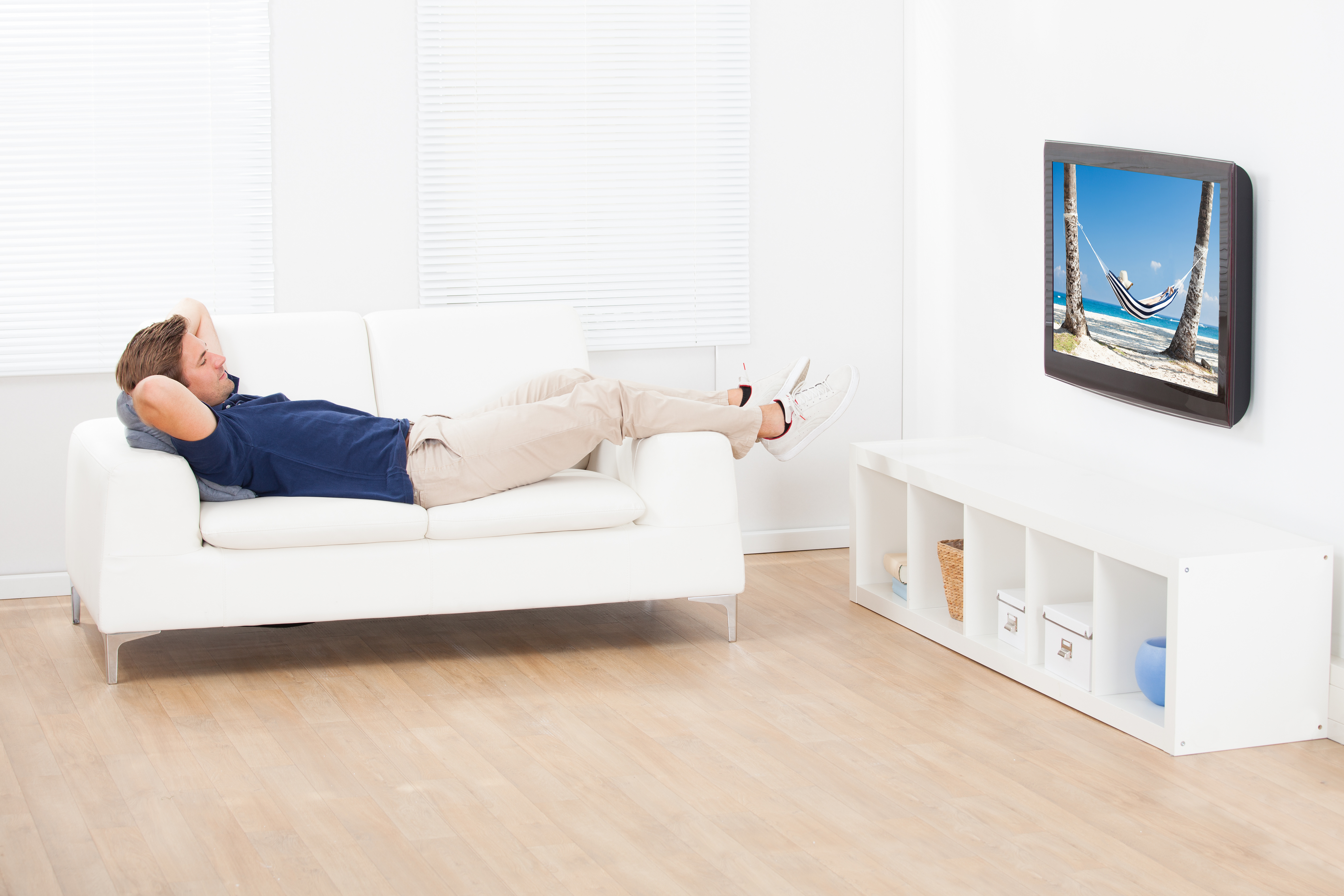 High angle view of man watching beach view on TV while relaxing at home