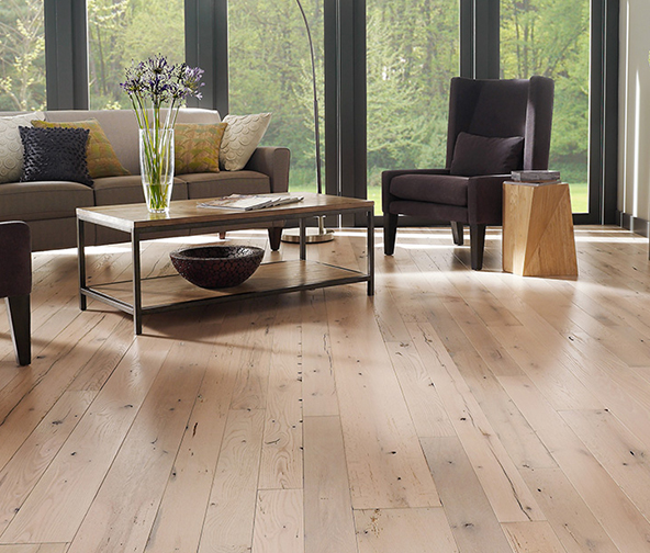 Living space with light wood flooring looking out on a forest