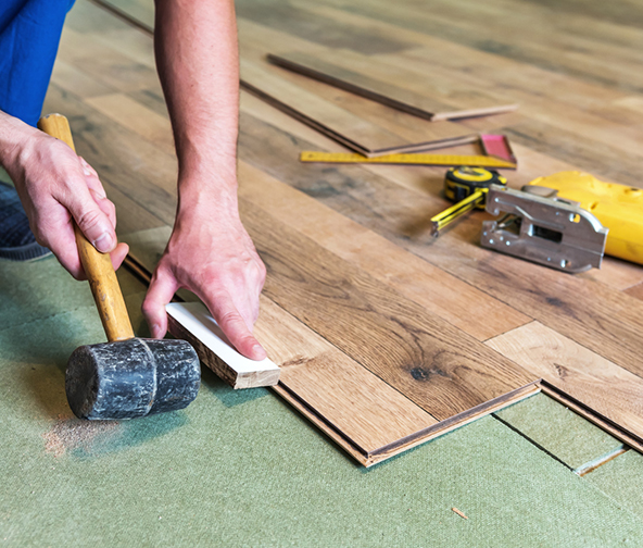Professional installing hardwood flooring plank by plank