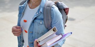 Student walking to class holding textbooks and notes